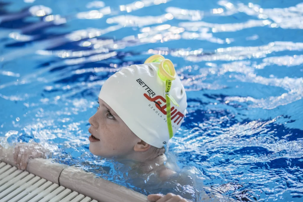 Chłopiec przy brzegu basenu z czepkiem BetterSwim
