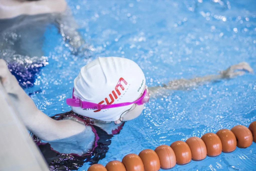 Dziewczynka w basenie z różowym czepkiem