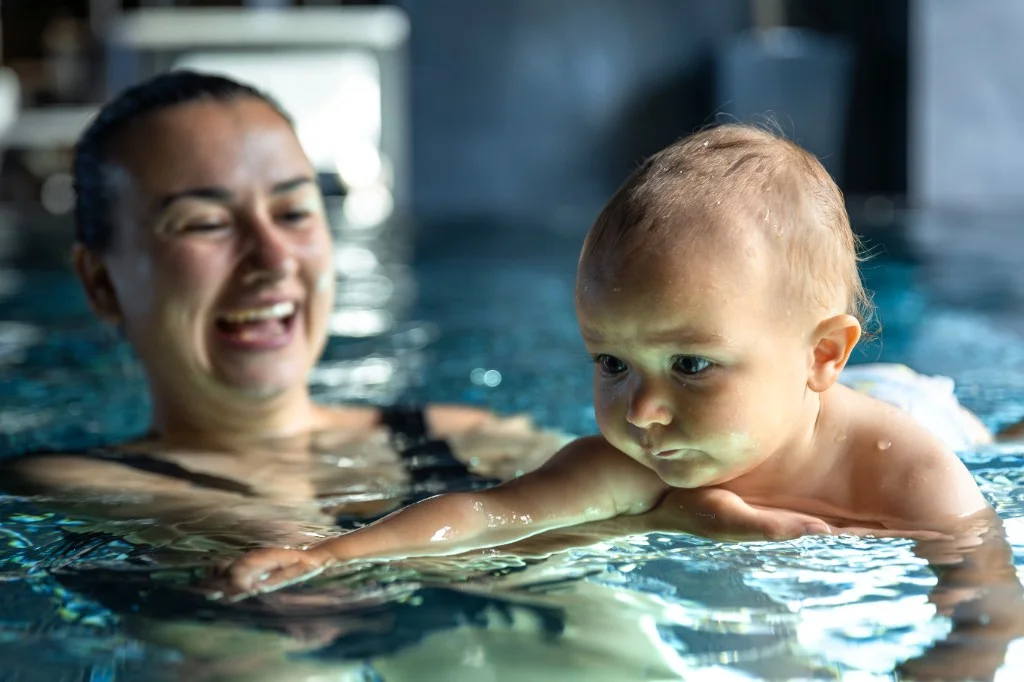 Mama z niemowlakiem na zajęciach nauki pływania w ciepłej wodzie